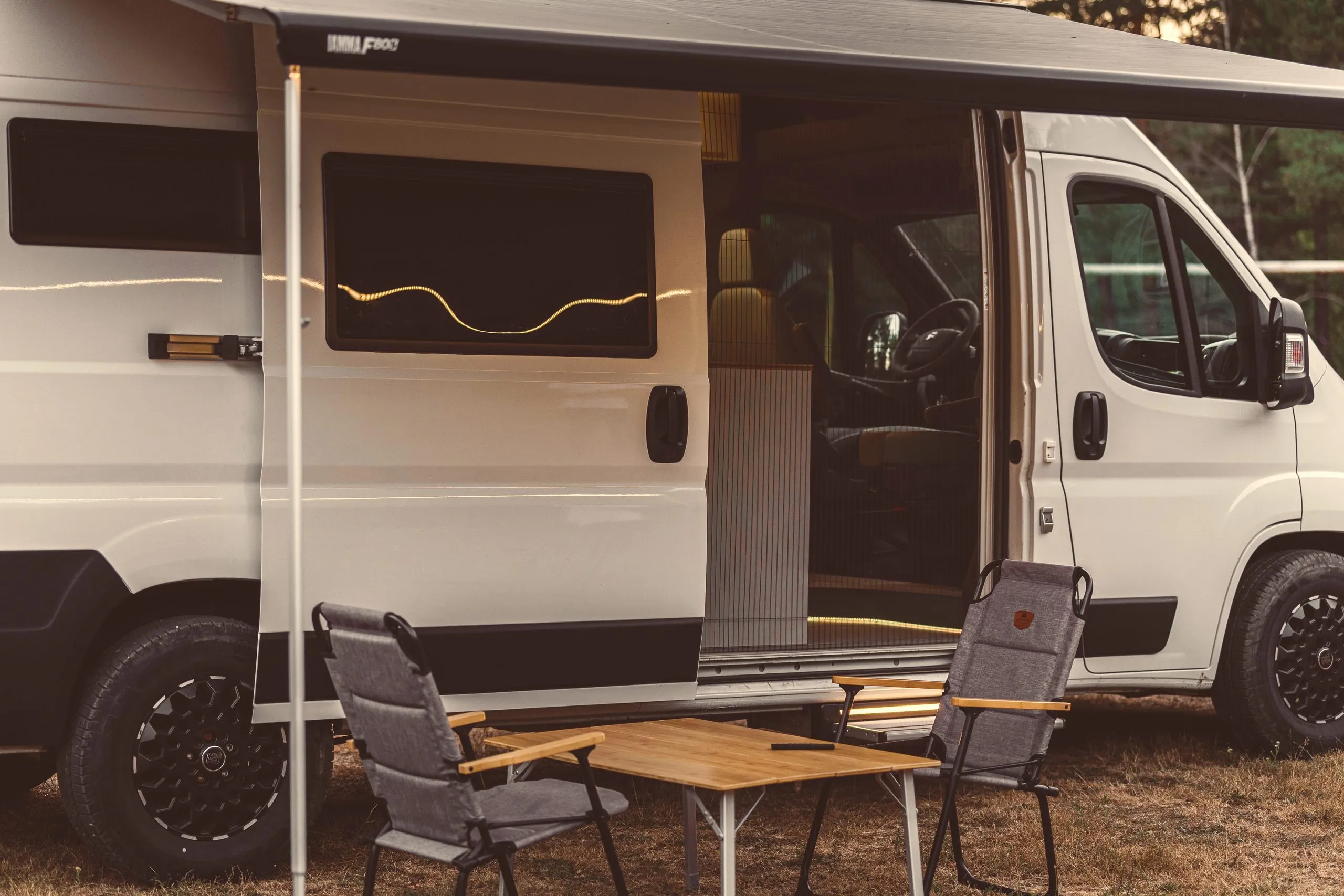 The van with its sliding door open and camping chairs outside