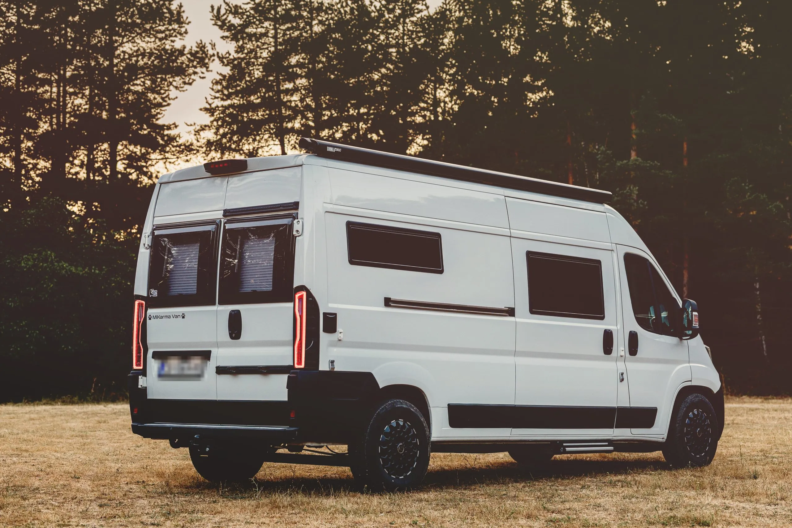 The van from behind at sunset, at the edge of a forest